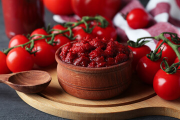 Bowl with tomato paste on dark wooden table with ingredients