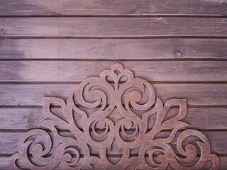 carved wooden ornament on a horizontal wooden boards background.