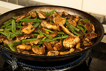 Friendo carne de pollo y de conejo para hacer paella valenciana.