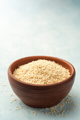 White sesame seeds in ceramic bowl on concrete background