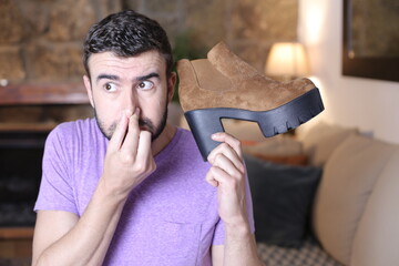 Disgusted man holding stinky shoe