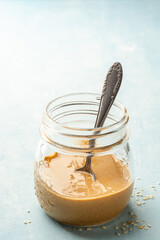 Homemade Tahini sauce in glass jar on concrete background