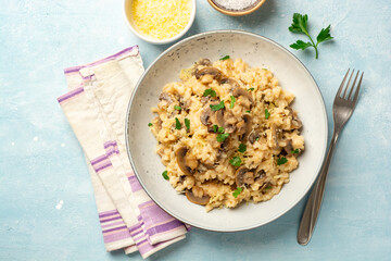Risotto with mushrooms, parmesan cheese and parsley in plate on concrete background
