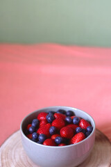 Bowl of blueberries and strawberries and wooden tray on a bed. Selective focus.