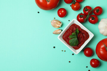 Bowl of tomato paste and ingredients on mint background