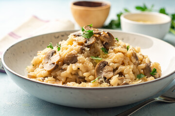 Risotto with mushrooms, parmesan cheese and parsley in plate on concrete background