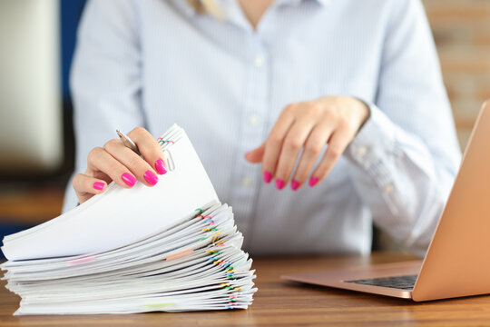 In Front Of Businesswoman Lies Large Pile Of Papers And Stands Laptop On Desktop