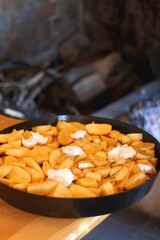 Preparing meat and potatoes under the iron bell ('peka') in the fireplace. Traditional rural meal in Croatia. Selective focus.