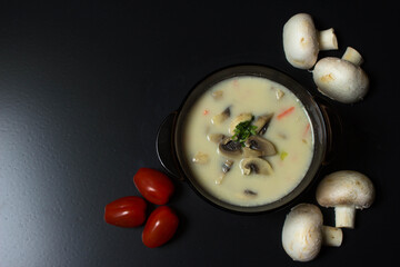 Plate with soup on a black background. Mushroom soup. Background. Appetizing soup.