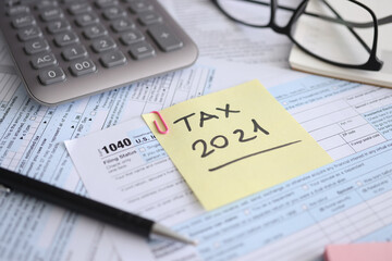 Tax form for 2021 and calculator with pen are on t table
