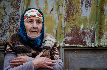 Grandmother on the background of slums. Lonely old woman. Old grandmother close up. Poverty and...