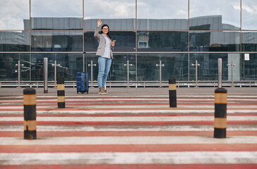 Fototapeta na wymiar Happy caucasian woman traveller in airport terminal with luggage