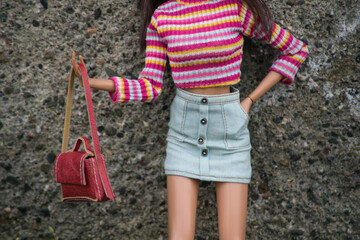  Closeup of mannequin doll wearing a mini blue jeans skirt, pink top and red handbag posing in the street