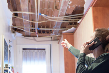 Woman explaining a kitchen ceiling incident to her homeowner's insurance company.