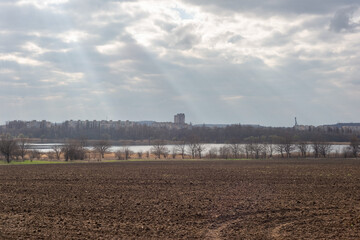 plowed field against the background of clouds and sunbeams. Spring cleaning of the land, preparation for planting crops