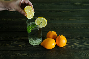 the hand which is squeezing out juice of a half of a lemon both three whole lemons and a segment of...