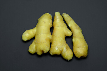 three roots of juicy fresh ginger on a gray background, photographed close-up