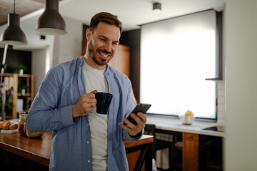 Naklejka na ściany i meble Handsome smiling man enjoying time for internet and coffee.