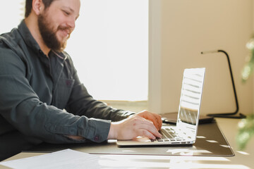 Male copywriter writing article on laptop at office.