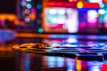 Rainy night in the city. Parking mall. Reflections of shop windows in a puddle on asphalt. Colorful...