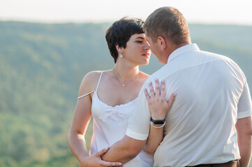 Newlyweds hug and kiss on the background of the forest. A man hugs and kisses a woman