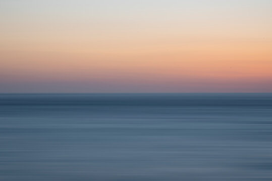 Beautiful long exposure landscape image of calm sea and colorful sunset sky