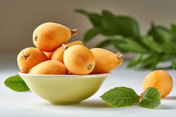 Loquat fruit. Nispero. Eriobotrya Japonica. Loquat in bowl with fresh leaves. Close up