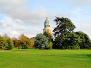 Old tower of church building viewed from behind trees and field