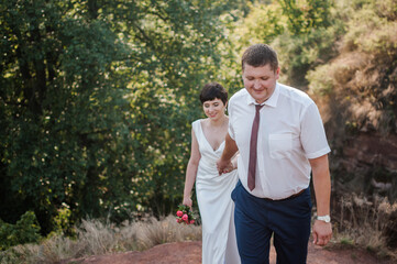 Obraz premium Newlyweds hold hands on the background of the forest
