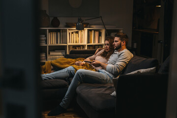 couple relaxing on sofa at home watching television