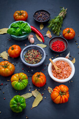 Assortment of organic tomatoes, spices and herbs on black background