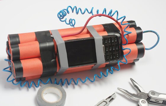 a bomb, a wire tool and an old mobile phone are being assembled on a white table as a timer before the explosion. the concept of terrorism and contract killing.