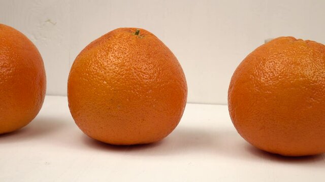 Ripe grapefruits stand in row on a white wooden table against the background of a white wooden panel