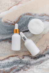 Fototapeta na wymiar two white bottle with dropper cap. On a marble background. The concept of beauty. Cosmetics for home care.