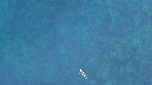 Aerial drone bird's eye view of fishing kayak cruise in tropical rocky seascape with crystal clear turquoise and sapphire waters