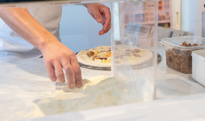 ピザ生地にチーズなどの具を乗せる　ピザを作るシーン　　