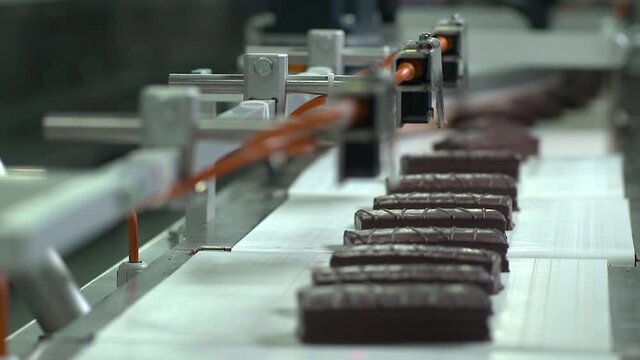 Production line in chocolate, biscuit, cake factory. Chocolate cake production line. Sweet foods on the production line. Cake moving on the conveyor belt. 
