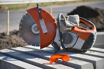 A circular saw stands on concrete curbs on a construction site.