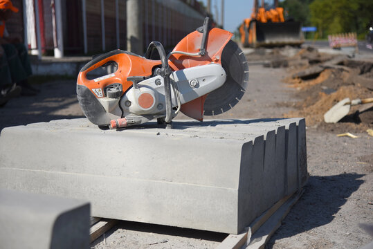 Circular saw stands on large concrete curbs, road repairs.