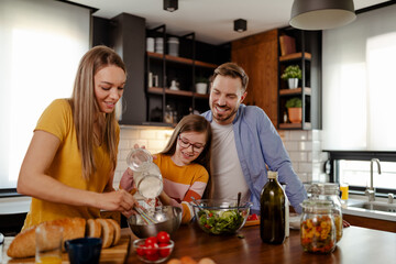 Mom, dad and daughter are cooking in kitchen. Man, young woman and little daughter are making lunch.