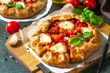 Healthy pastries gluten free, made from rye flour, diet food. Galette tomatoes, mozzarella and basil on a stone background.