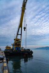 Fototapeta na wymiar Batumi, Georgia - 08 February 2021: Yellow crane in a cargo port, industrial scene
