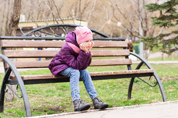 A lonely girl sits with a sad face on a park bench. Mental health. Teenage years