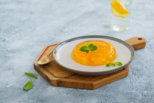Dessert, orange jelly on a ceramic plate on a light concrete background.