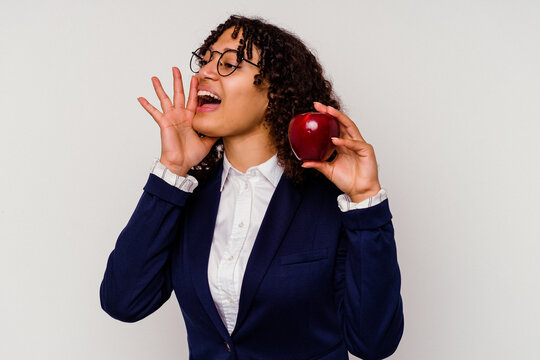 Young business mixed race woman holding a red apple isolated on white background shouting and holding palm near opened mouth.
