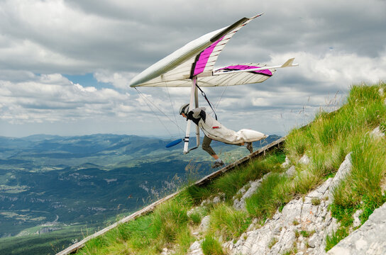 Hang glider pilots runs from steep slope high in the mountains in Uchka, Croatia.