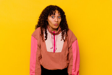 Young mixed race woman isolated on pink background shrugs shoulders and open eyes confused.