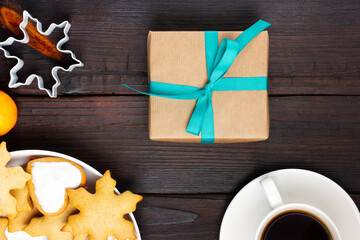 A plate with Christmas cookies and a gift box on a wooden table. Festive Christmas present.