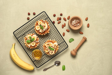 Homemade Belgian waffles with banana, nuts and honey. Beige concrete background. Top view, flat lay.