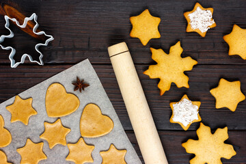 The process of making Christmas cookies. Wooden rolling pin and dough in the form of Christmas cookies. View from above.